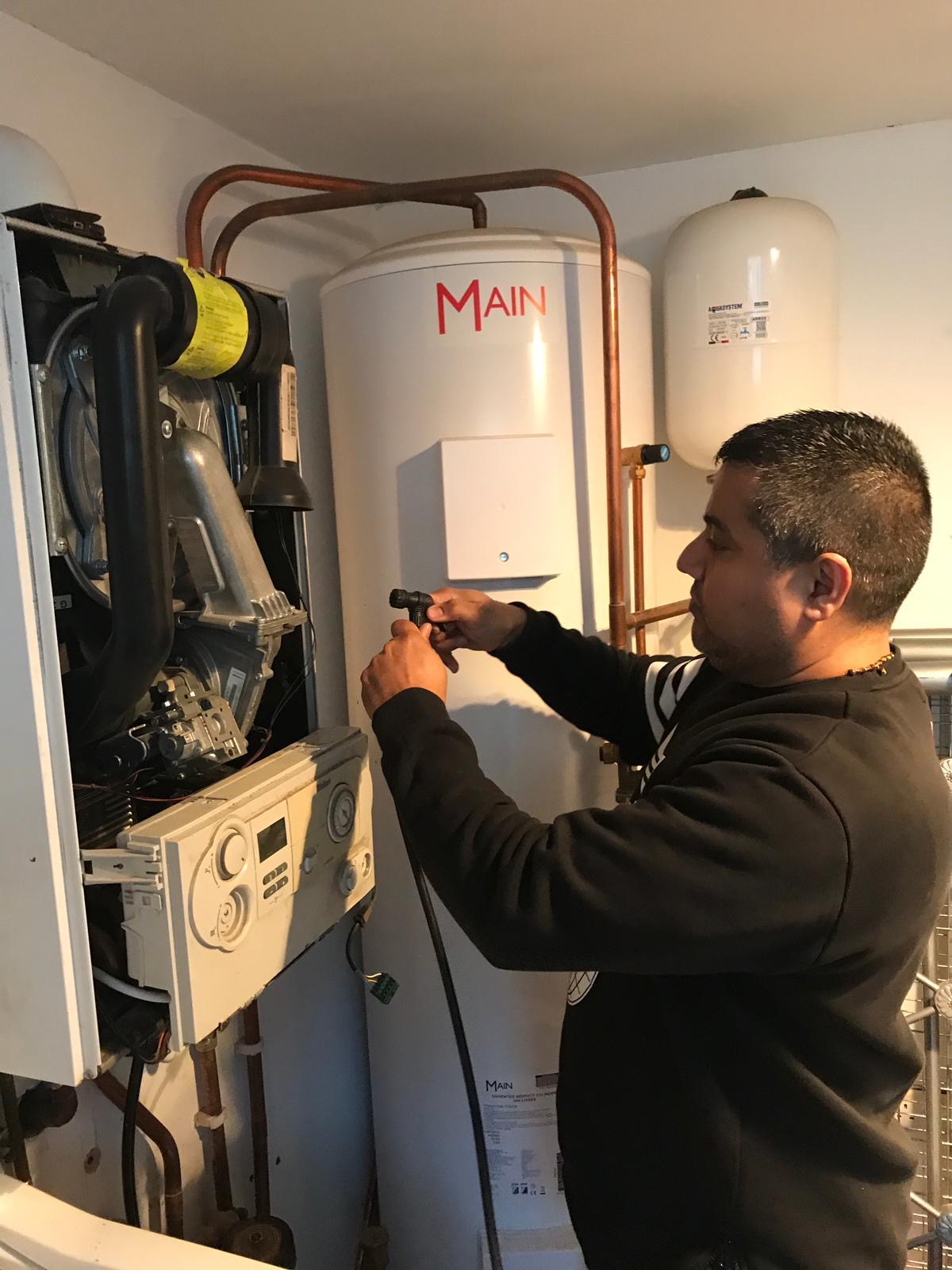 Sandeep working on an open boiler beside a hot water cylinder