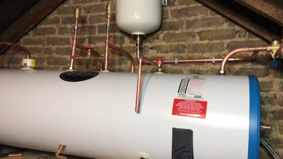Hot water cylinder and copper pipework installed in a loft space